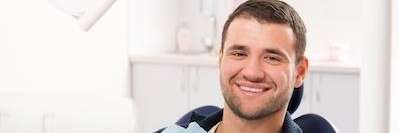 man smiling in dental exam chair | dentist grand rapids